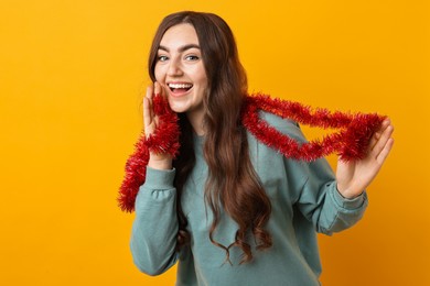 Photo of Happy young woman with tinsel on orange background