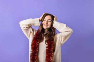 Photo of Happy young woman with tinsel on purple background