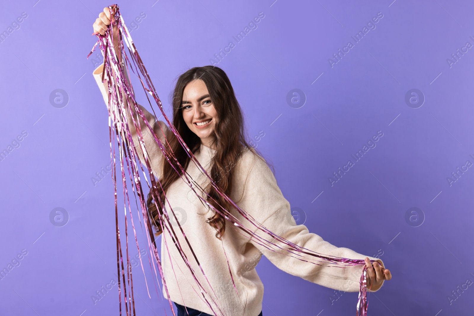 Photo of Happy young woman with tinsel on purple background. Space for text