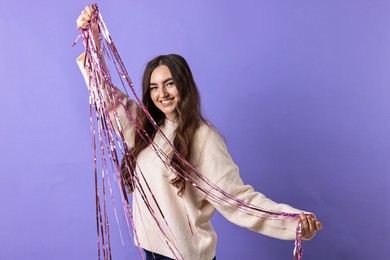 Happy young woman with tinsel on purple background. Space for text