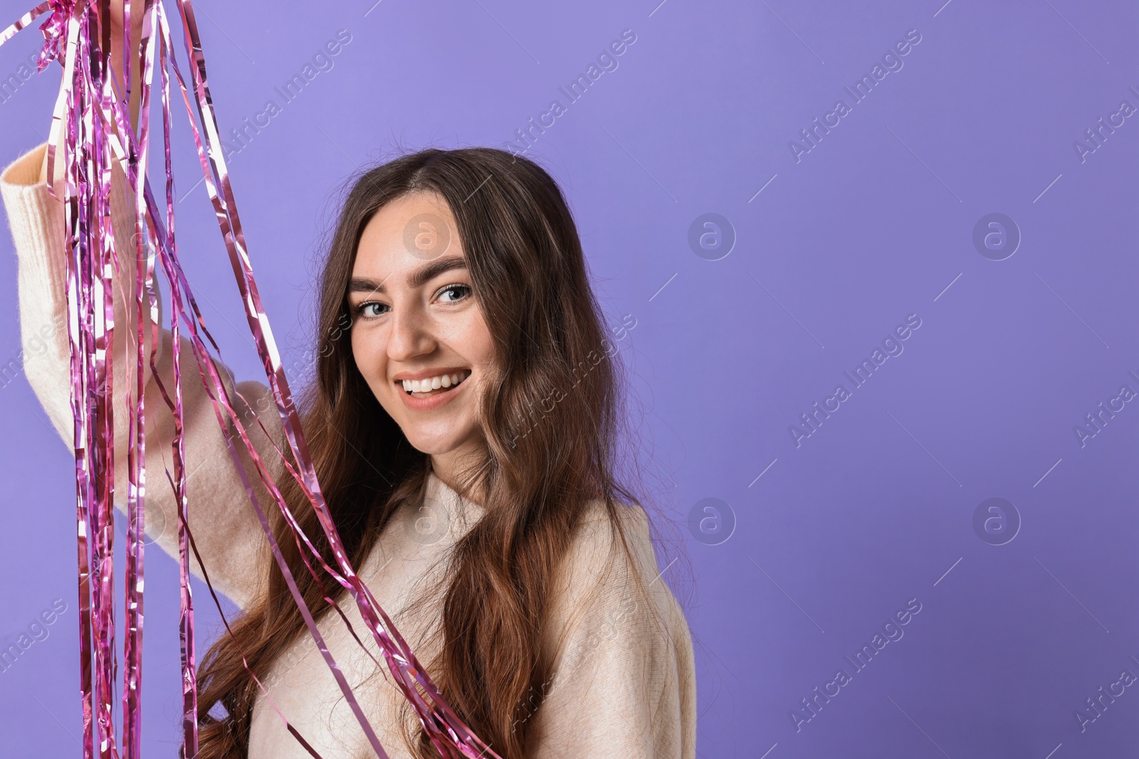 Photo of Happy young woman with tinsel on purple background. Space for text