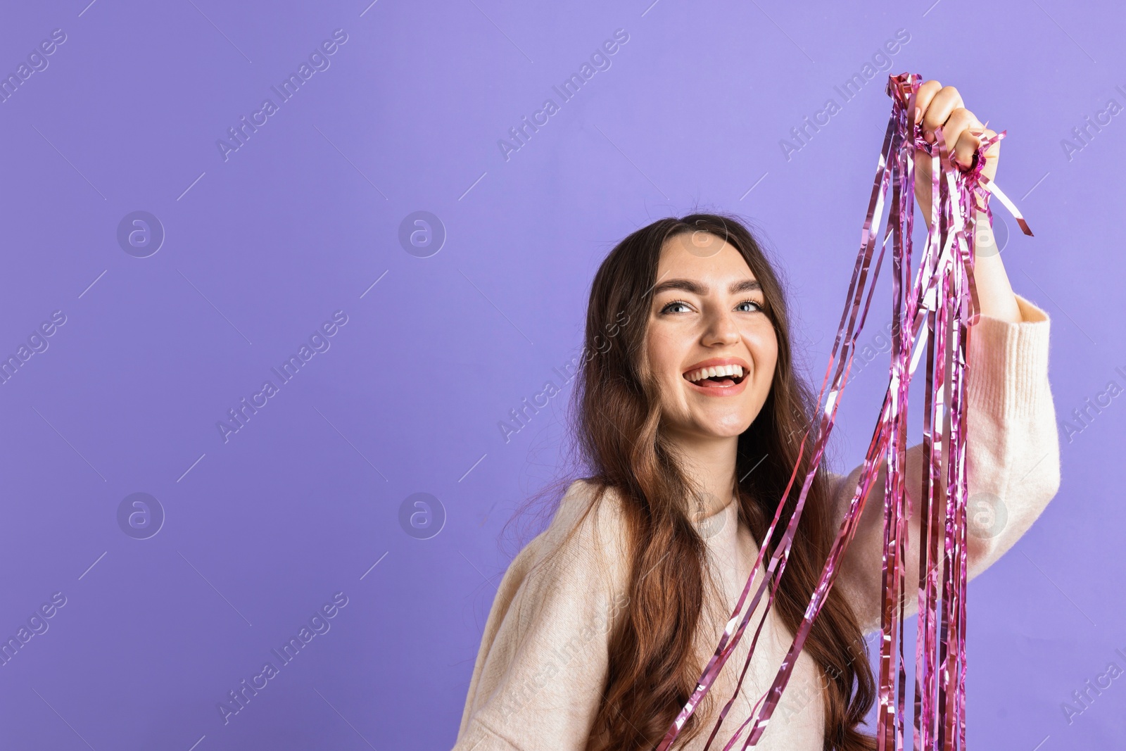 Photo of Happy young woman with tinsel on purple background. Space for text