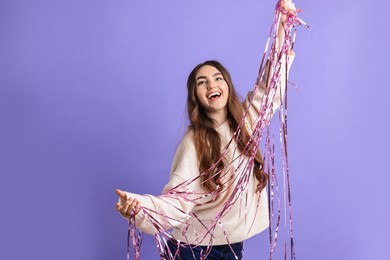 Photo of Happy young woman with tinsel on purple background. Space for text