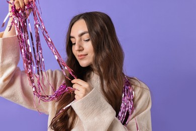 Photo of Beautiful young woman with bright tinsel on purple background