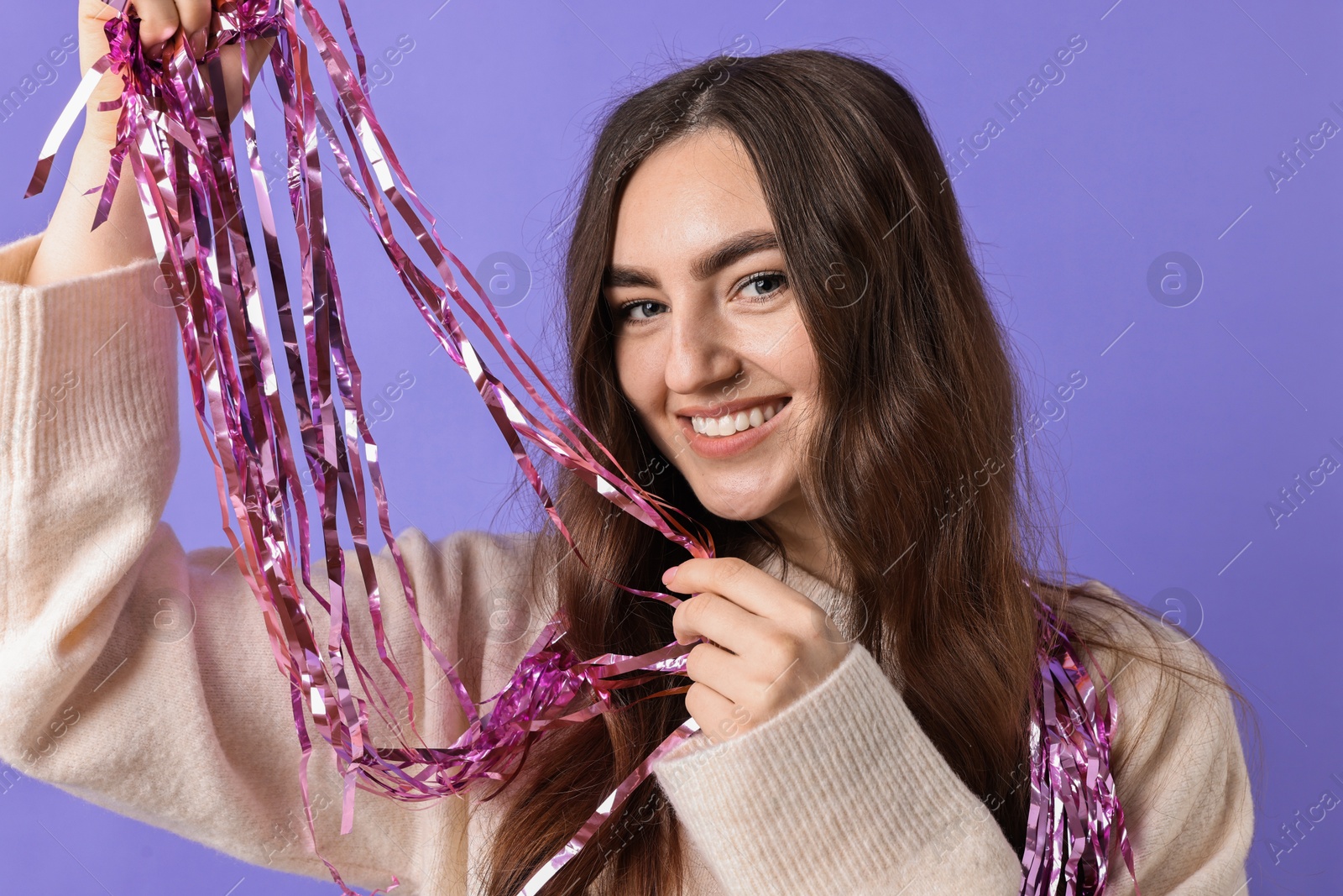 Photo of Happy young woman with tinsel on purple background