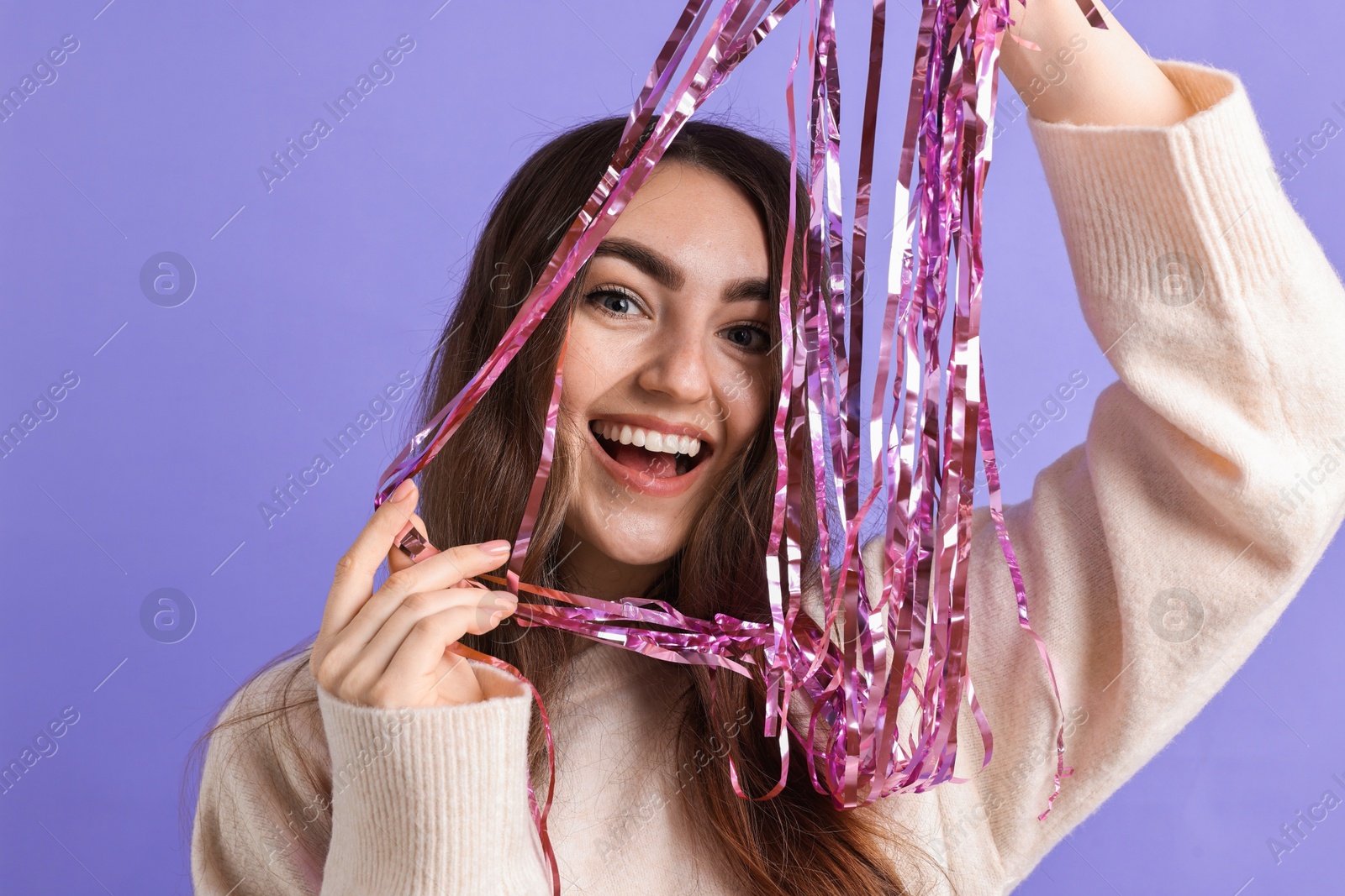 Photo of Happy young woman with tinsel on purple background