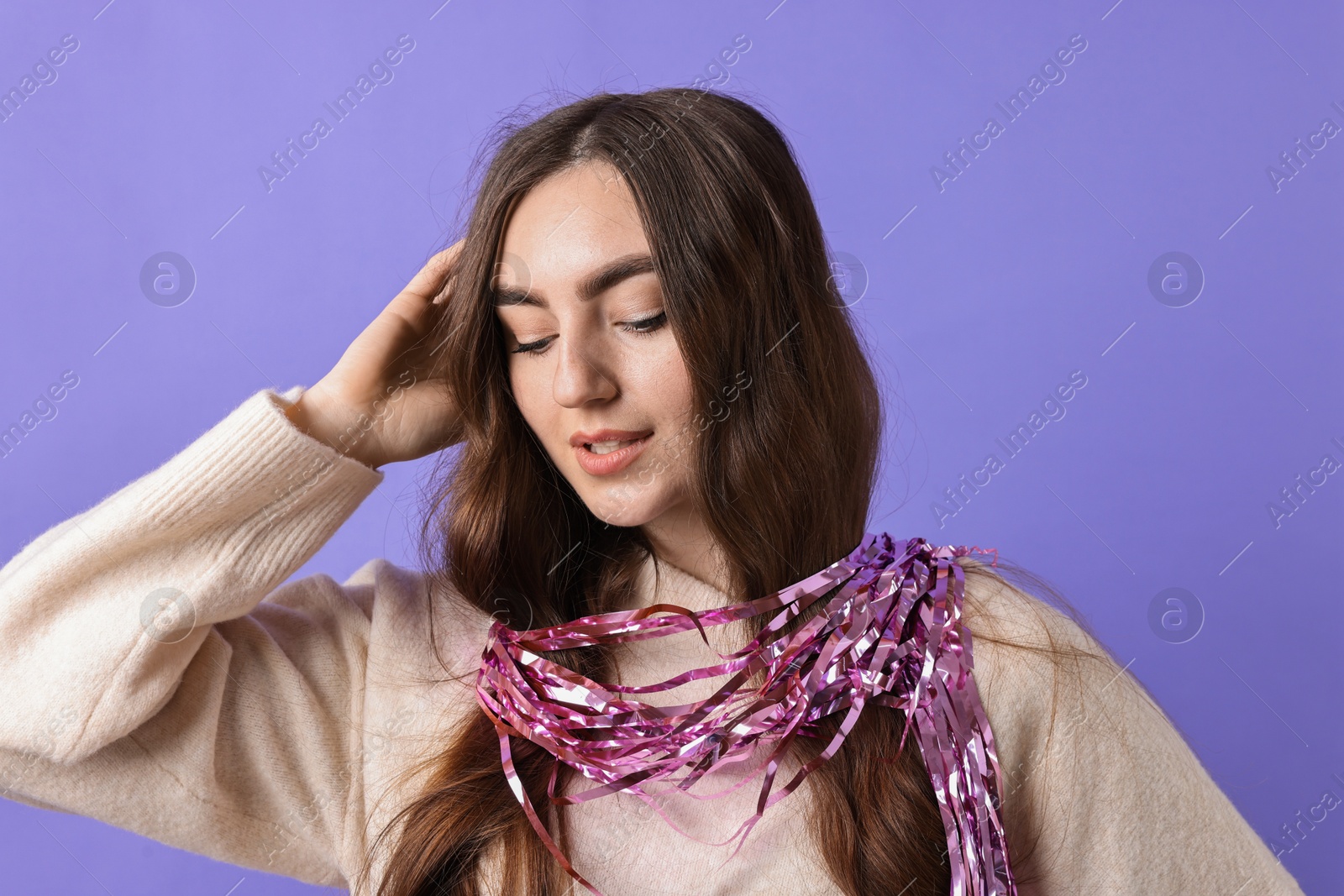 Photo of Beautiful young woman with bright tinsel on purple background