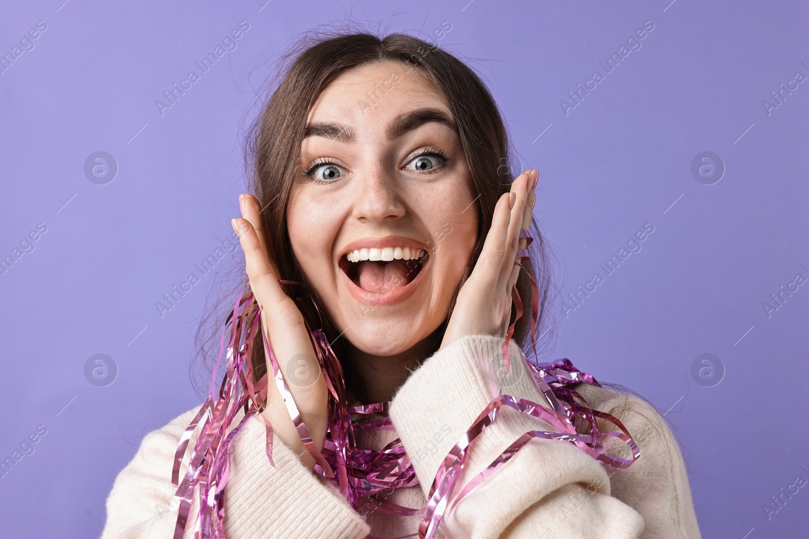 Photo of Excited young woman with bright tinsel on purple background