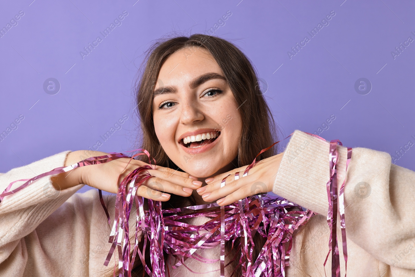 Photo of Happy young woman with tinsel on purple background