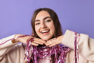 Photo of Happy young woman with tinsel on purple background