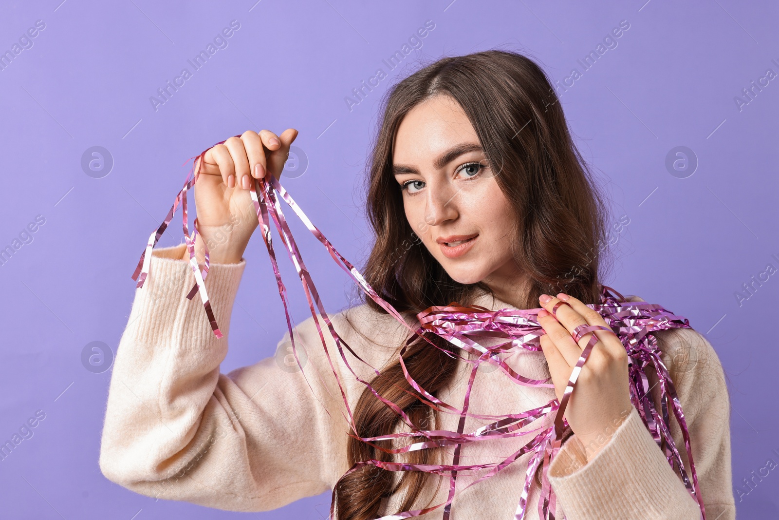 Photo of Beautiful young woman with bright tinsel on purple background