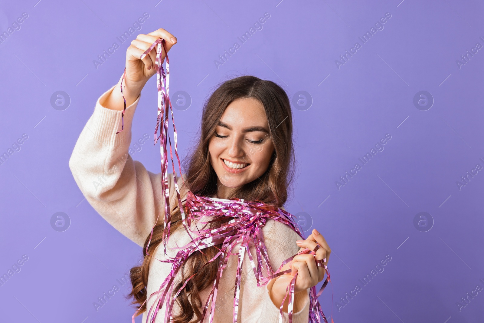 Photo of Happy young woman with tinsel on purple background