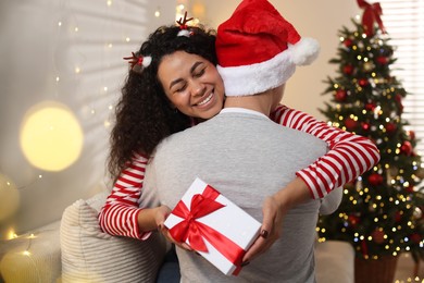 Photo of Happy couple with Christmas gift hugging at home