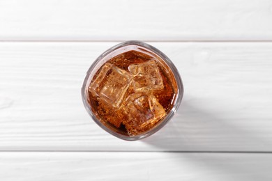 Photo of Sweet soda water with ice cubes in glass on white wooden table, top view