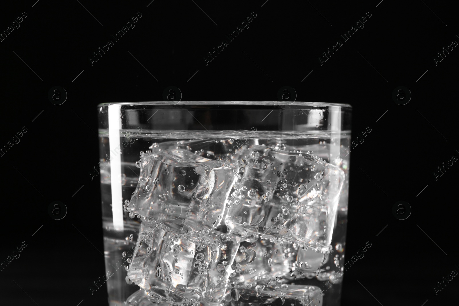 Photo of Refreshing soda water with ice cubes in glass on black background, closeup