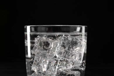 Photo of Refreshing soda water with ice cubes in glass on black background, closeup