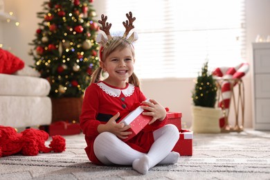 Photo of Little girl in Christmas costume with gift boxes at home