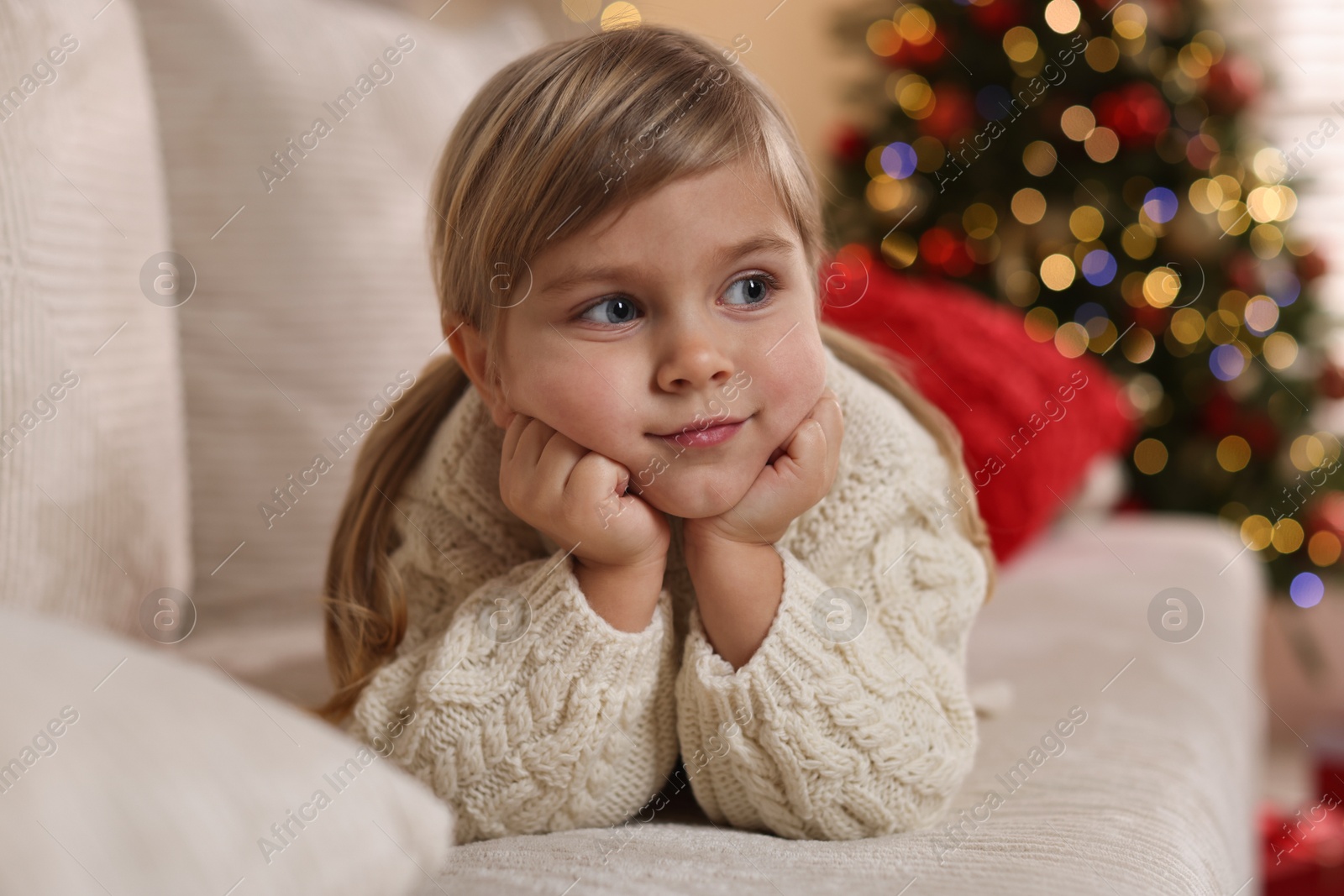 Photo of Little girl lying on sofa at home. Christmas celebration