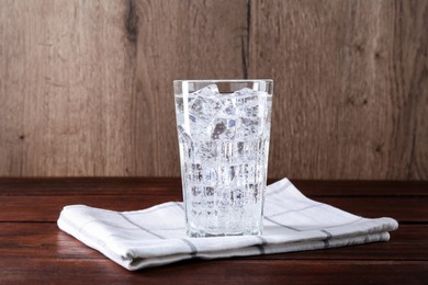 Photo of Refreshing soda water with ice cubes in glass on wooden table