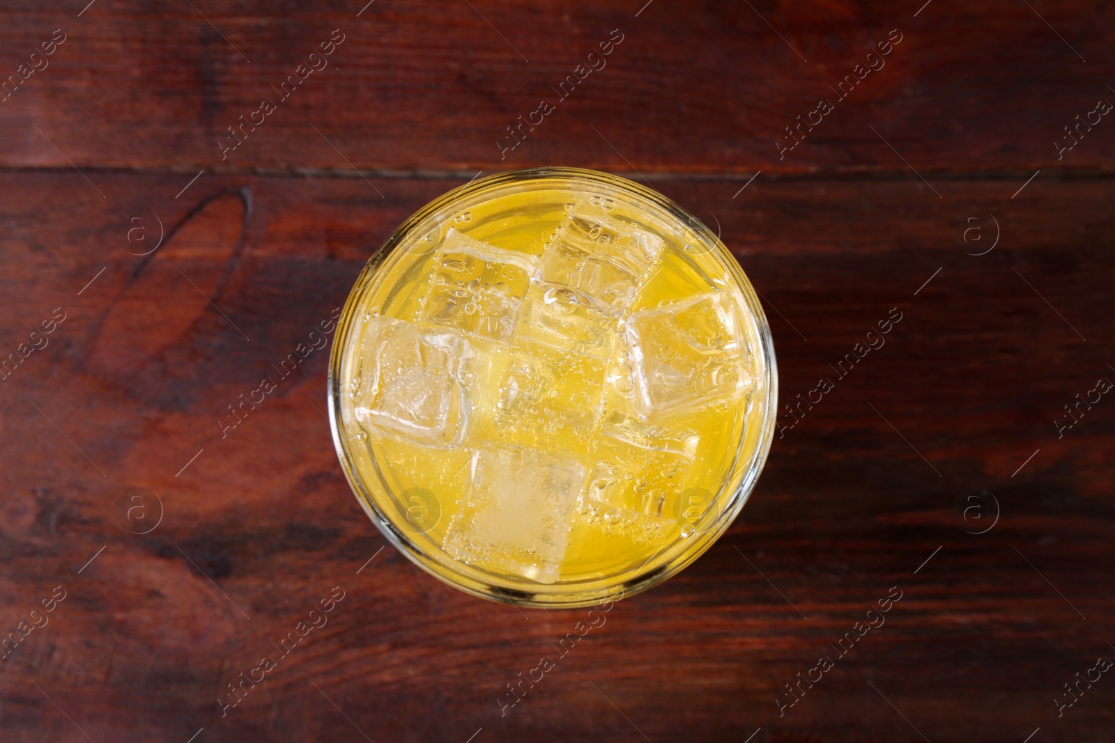 Photo of Sweet soda water with ice cubes in glass on wooden table, top view