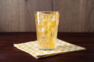 Photo of Sweet soda water with ice cubes in glass on wooden table