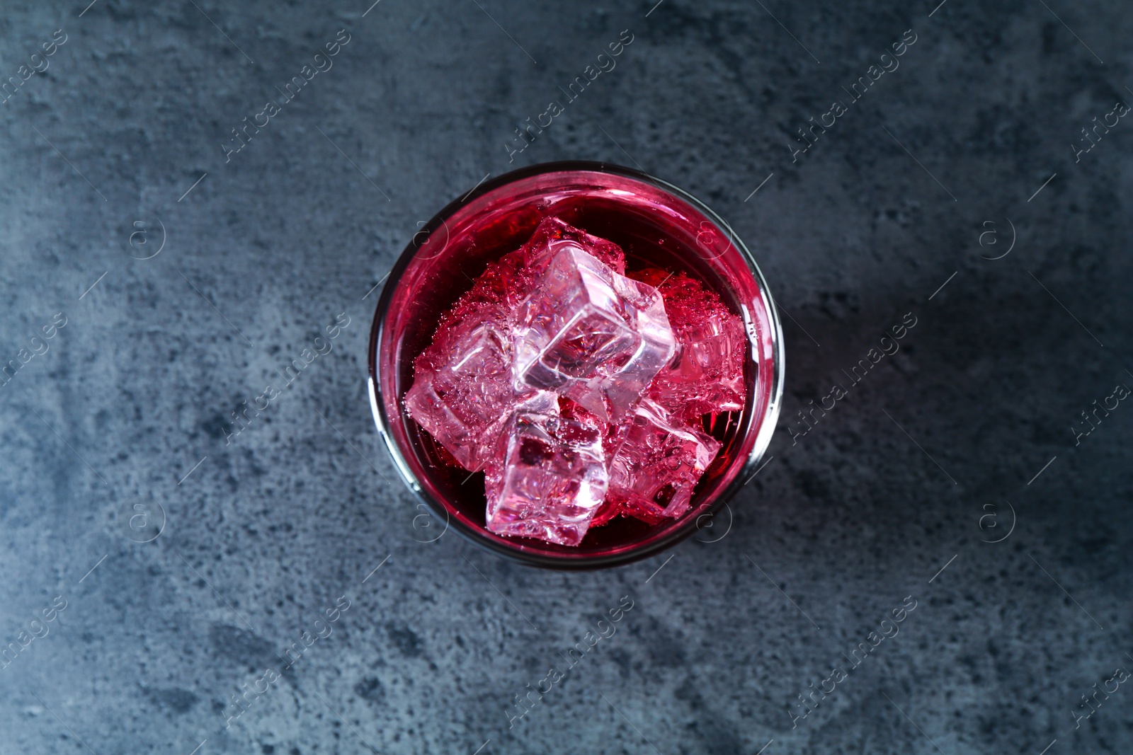 Photo of Sweet soda water with ice cubes in glass on grey table, top view