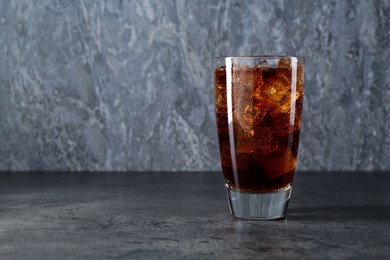 Photo of Sweet soda water with ice cubes in glass on grey table, space for text