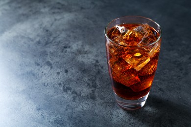 Photo of Sweet soda water with ice cubes in glass on grey table, space for text