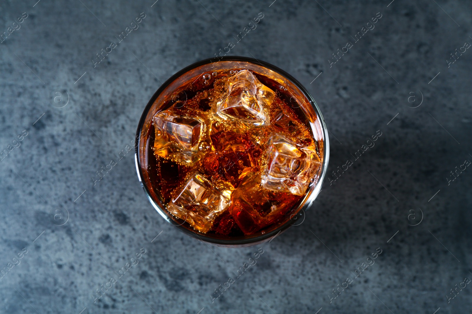 Photo of Sweet soda water with ice cubes in glass on grey table, top view