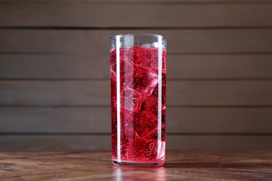 Photo of Sweet soda water with ice cubes in glass on wooden table