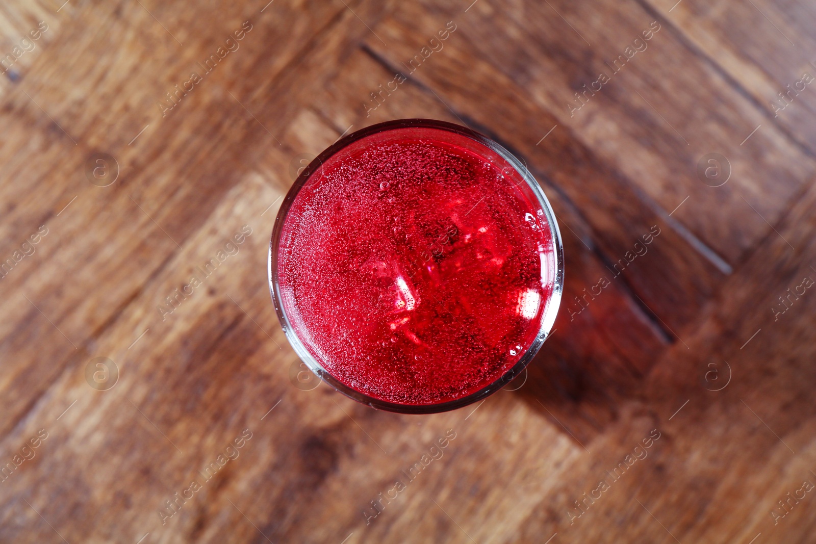 Photo of Sweet soda water with ice cubes in glass on wooden table, top view