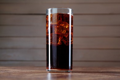 Photo of Sweet soda water with ice cubes in glass on wooden table