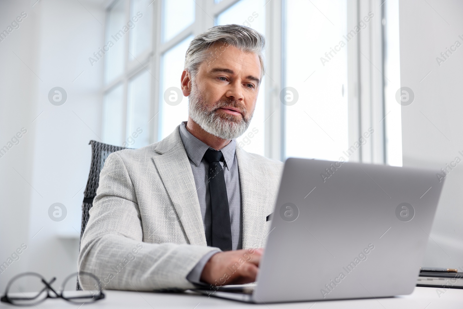 Photo of Banker working on laptop at desk in office