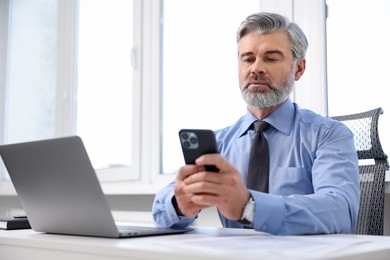 Photo of Banker with smartphone at desk in office