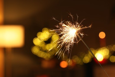 Photo of Bright burning sparkler on blurred background, space for text. Bokeh effect