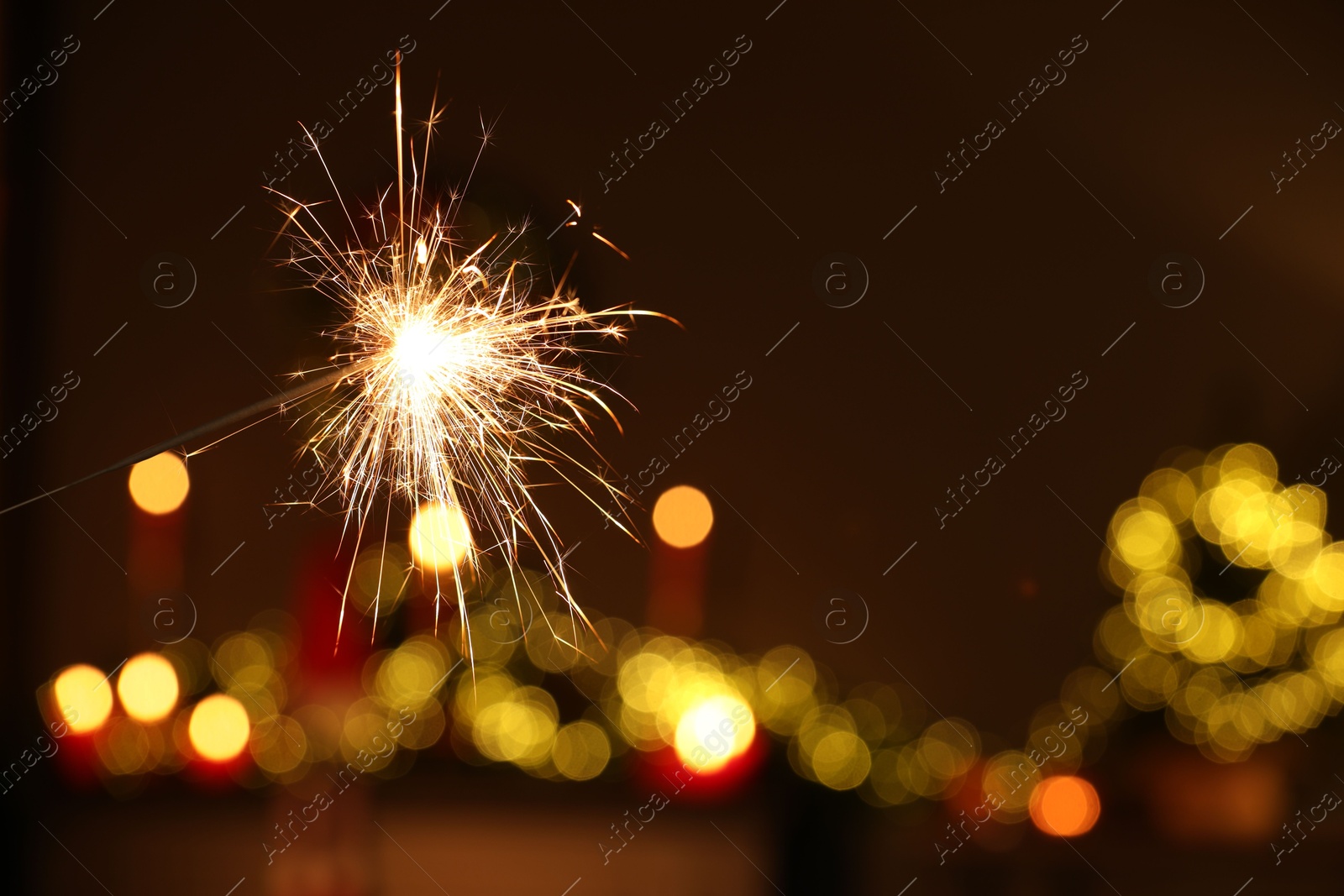 Photo of Bright burning sparkler on blurred background, space for text. Bokeh effect