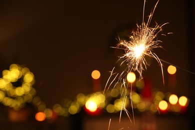 Photo of Bright burning sparkler on blurred background, space for text. Bokeh effect