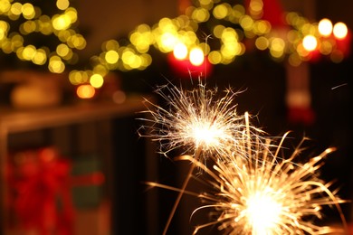 Photo of Bright burning sparklers on blurred background, space for text. Bokeh effect