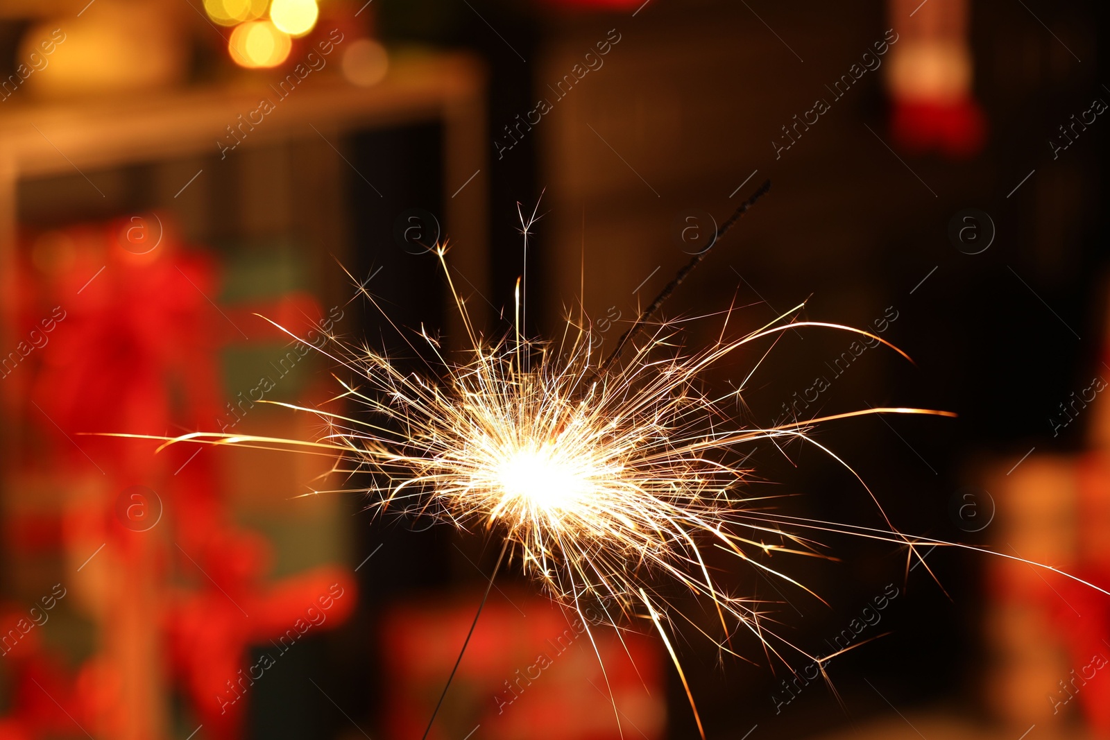 Photo of Bright burning sparkler on blurred background, bokeh effect