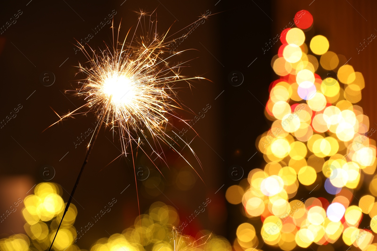 Photo of Bright burning sparkler on blurred background, space for text. Bokeh effect