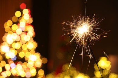 Photo of Bright burning sparkler on blurred background, space for text. Bokeh effect