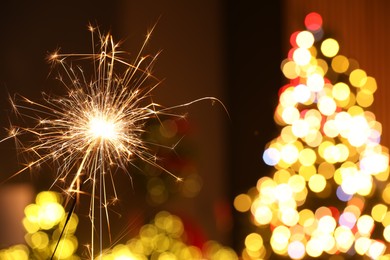 Photo of Bright burning sparkler on blurred background, space for text. Bokeh effect