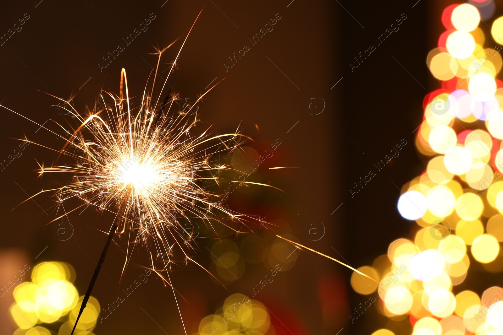 Photo of Bright burning sparkler on blurred background, space for text. Bokeh effect