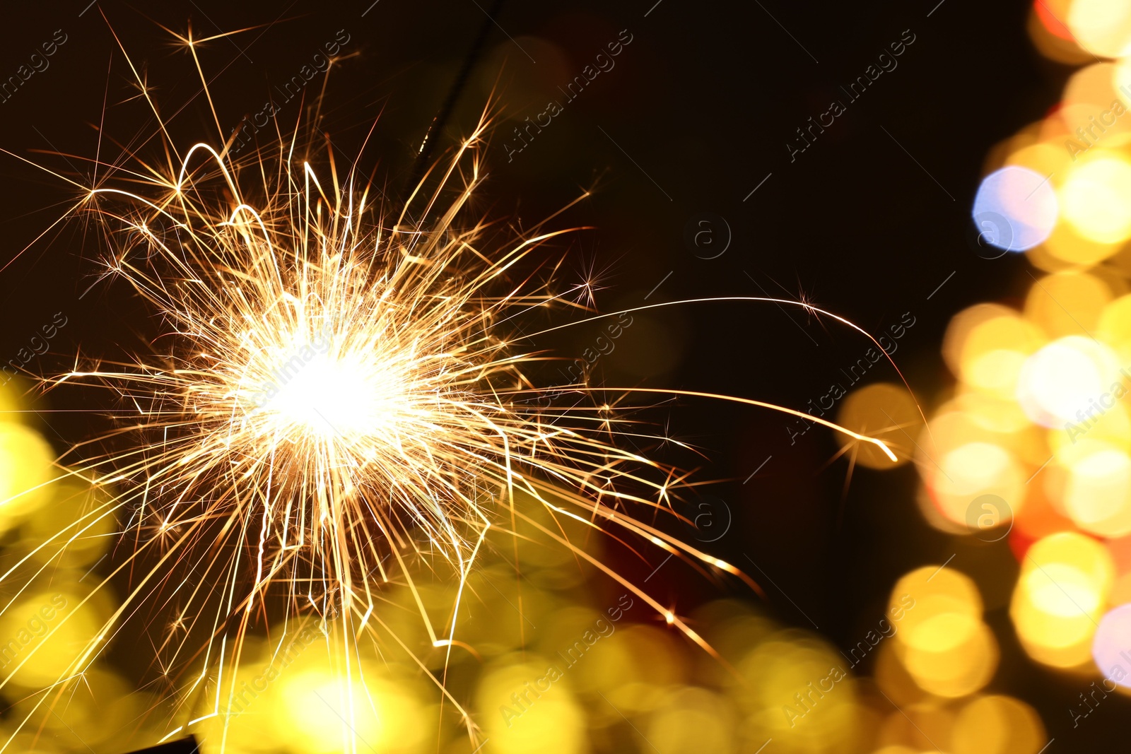 Photo of Bright burning sparkler on blurred background, space for text. Bokeh effect