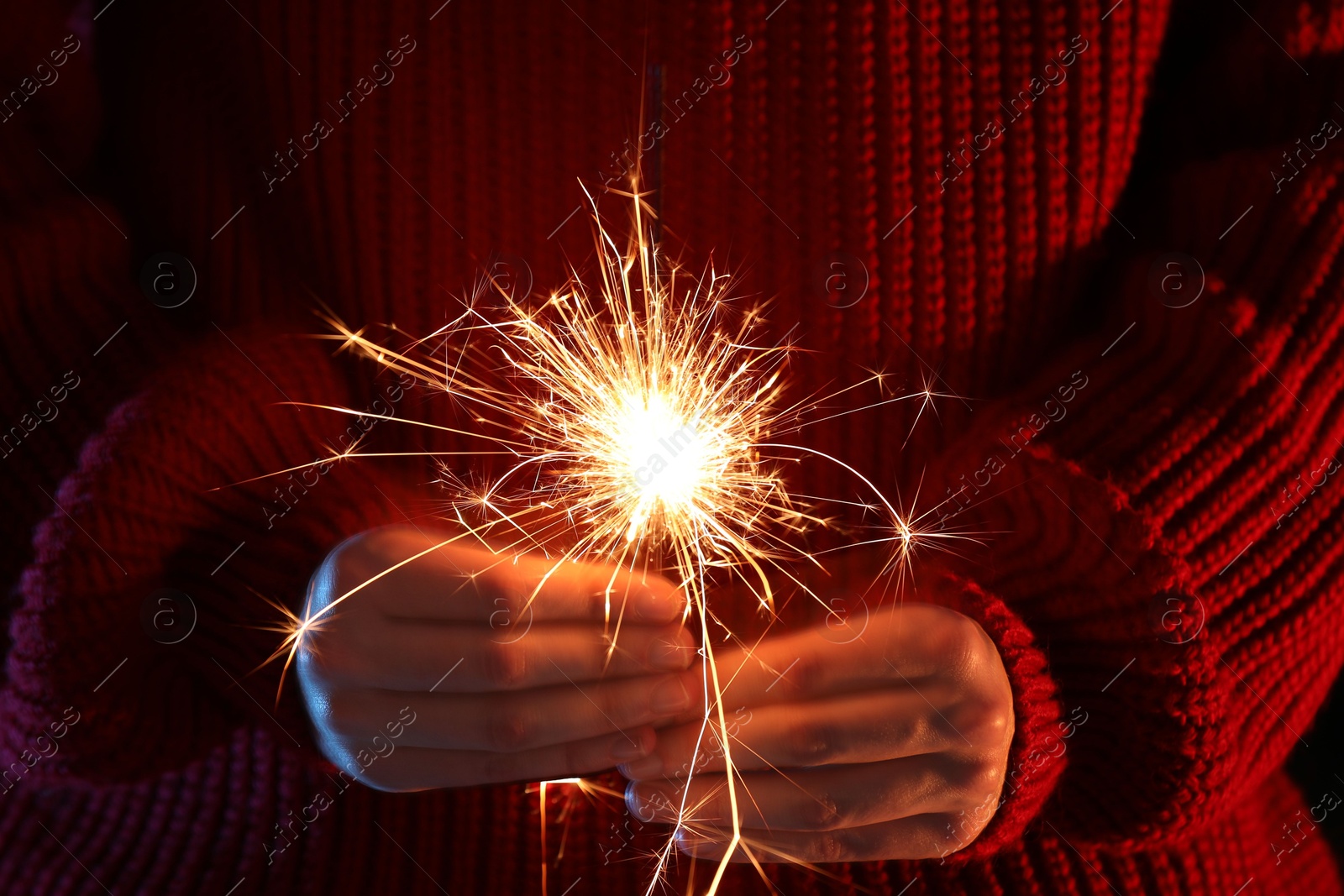 Photo of Woman with bright burning sparkler, closeup view