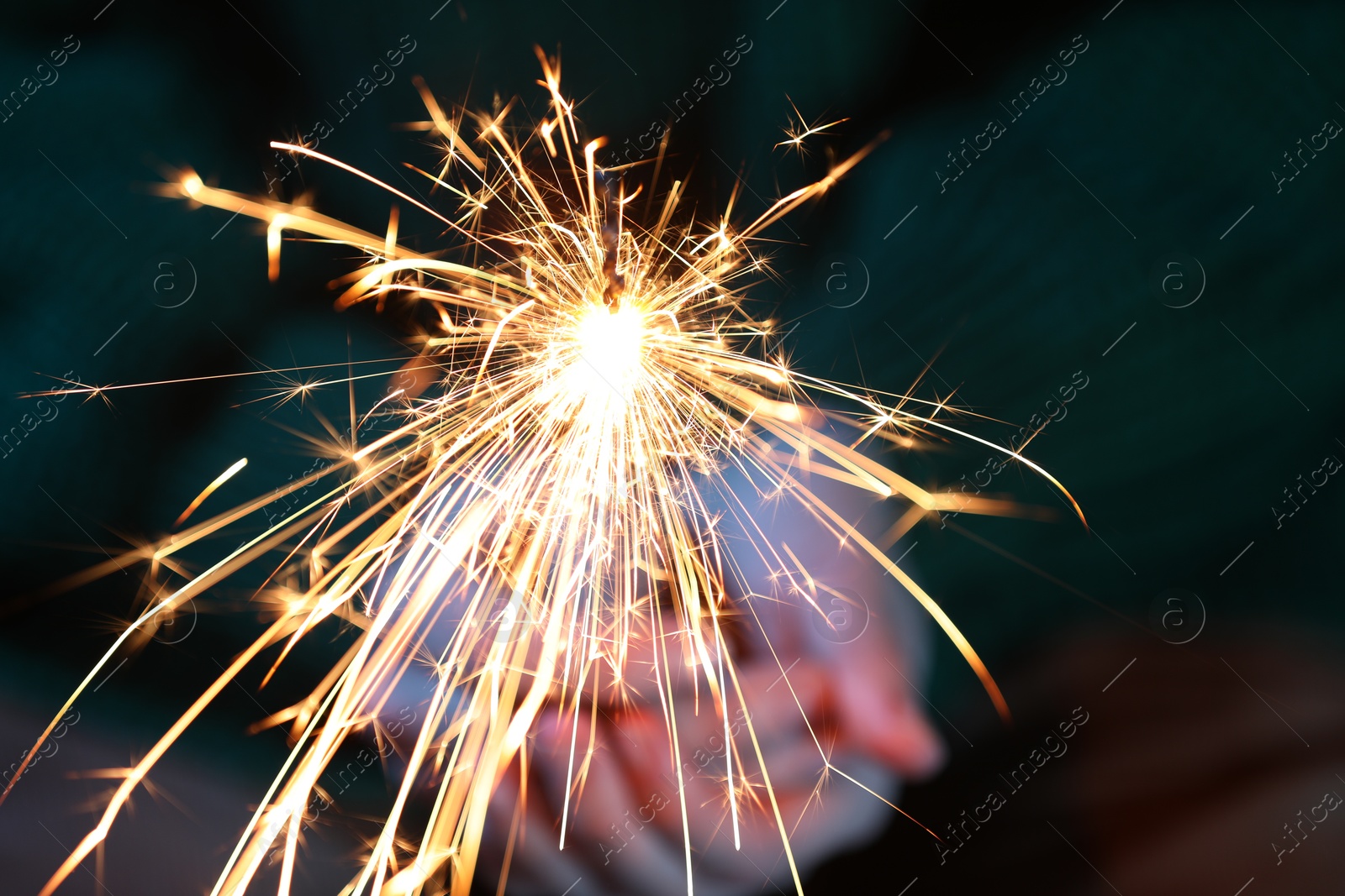 Photo of Woman with bright burning sparkler, closeup view