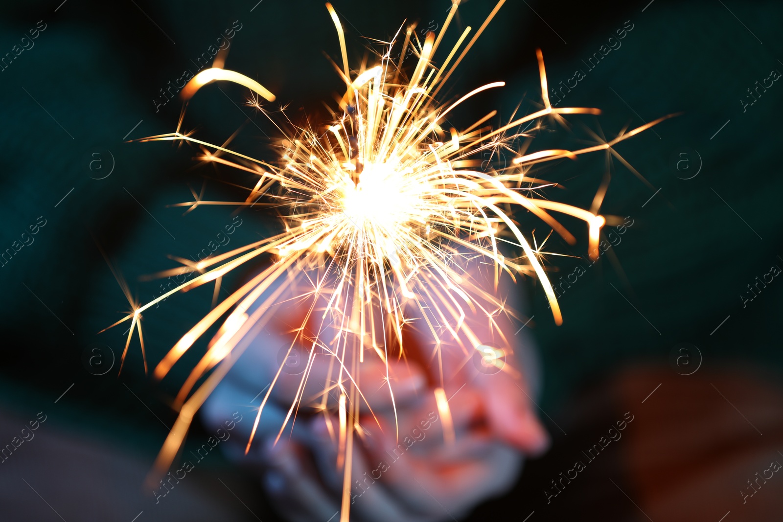 Photo of Woman with bright burning sparkler, closeup view