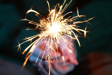 Photo of Woman with bright burning sparkler, closeup view