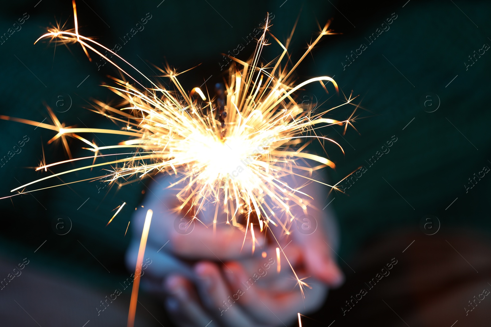 Photo of Woman with bright burning sparkler, closeup view