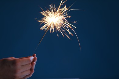 Photo of Man with bright burning sparkler on light blue background, closeup. Space for text